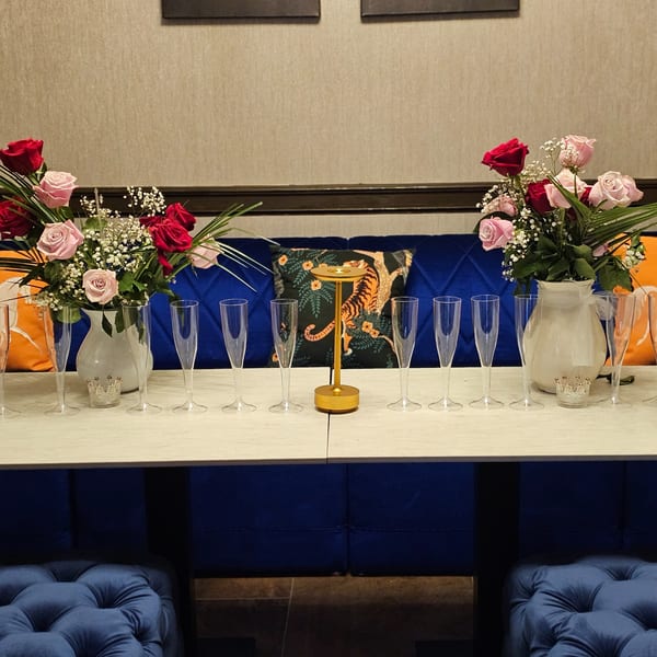 Table set with champagne flutes, rose bouquets, and a golden centerpiece at The Opulent Restaurant.