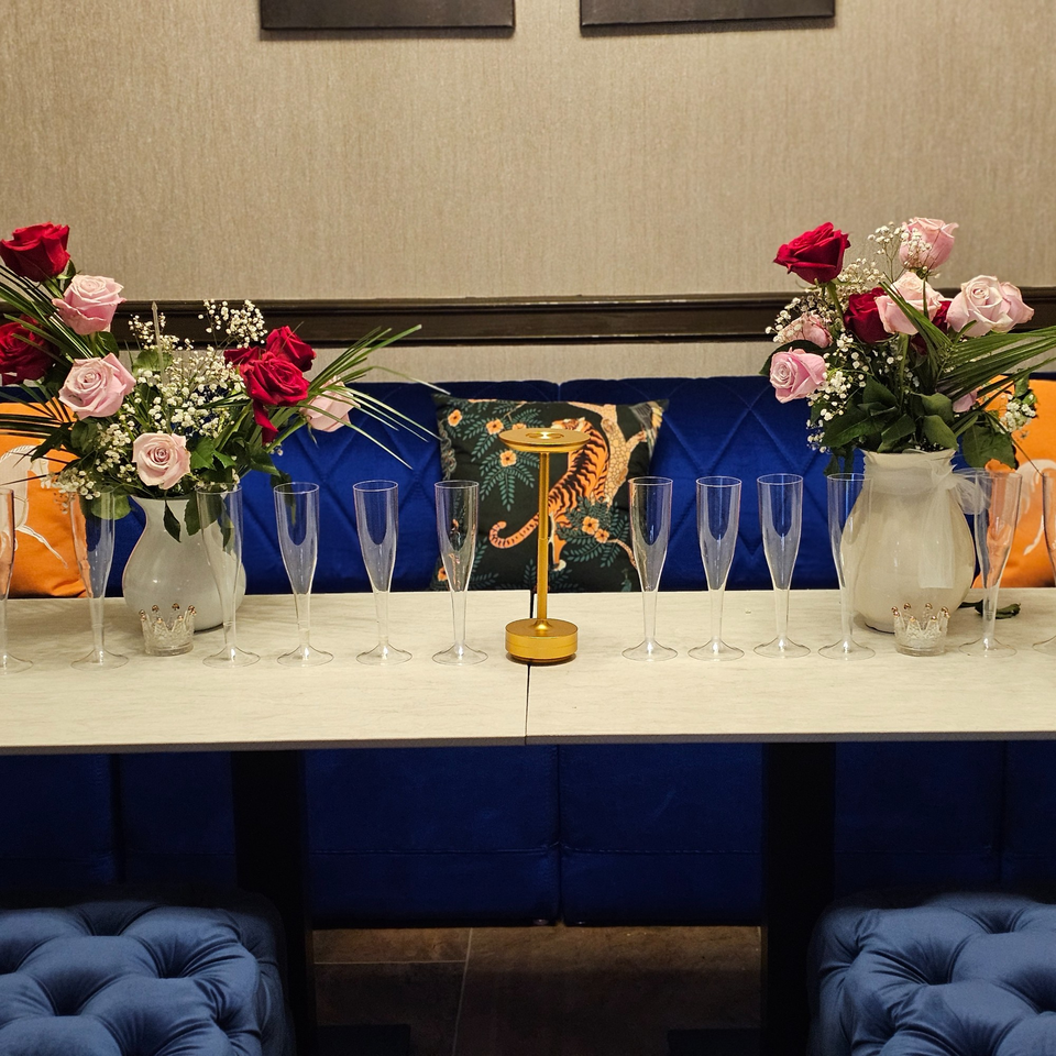 Table set with champagne flutes, rose bouquets, and a golden centerpiece at The Opulent Restaurant.