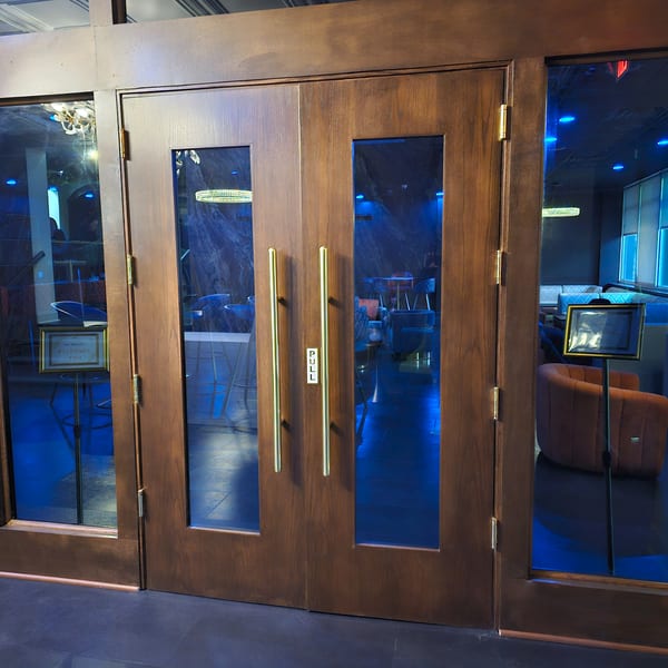 The Opulent Restaurant and Lounge entrance with dark wood doors, glass panels, and blue interior lighting.