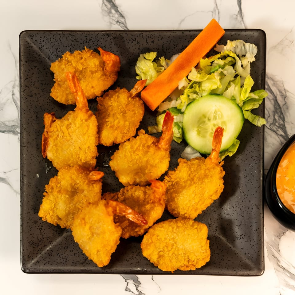 Crispy fried shrimp with a side of fresh lettuce, cucumber, carrot, and a dipping sauce.