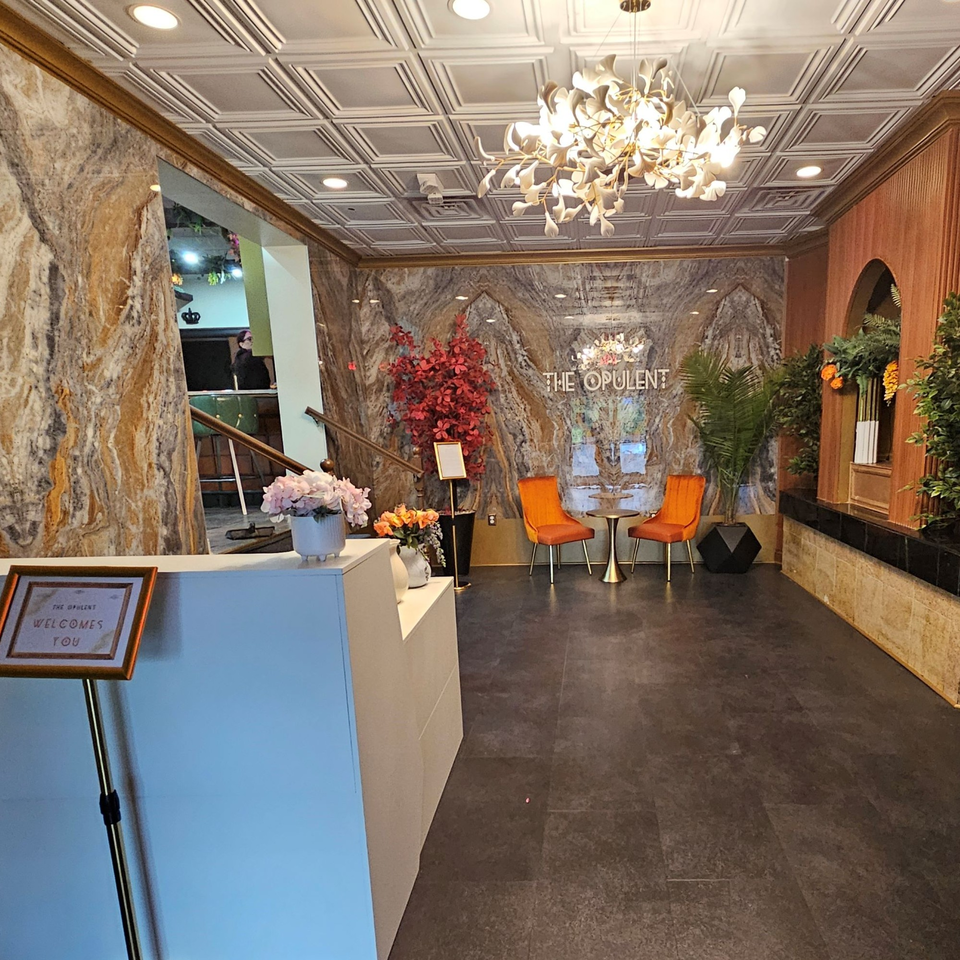 The Opulent Restaurant and Lounge's elegant lobby with a welcome desk, seating, and ornate decor.