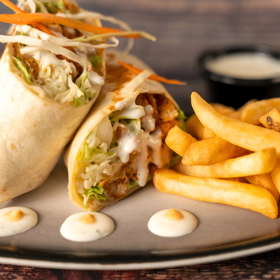 Two Indian chicken wraps with lettuce, cabbage, and sauce, served with golden french fries.