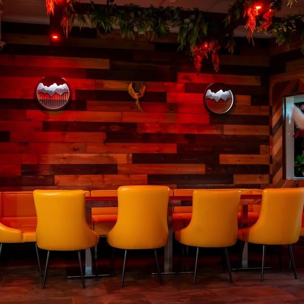 The Opulent Restaurant and Lounge interior with yellow chairs, orange booths, and red-lit wooden walls.