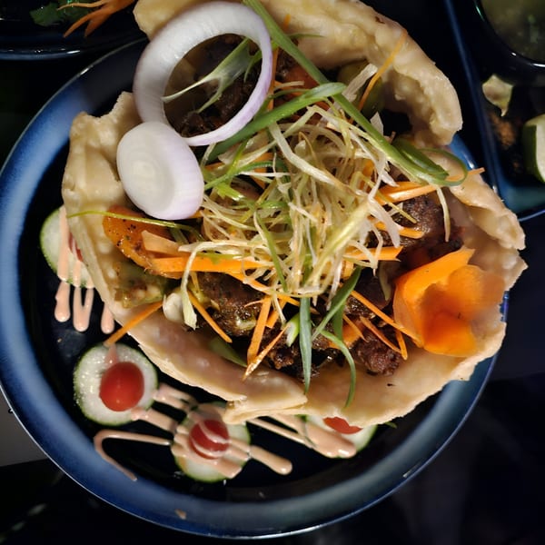 Indian street food dish with meat, shredded vegetables, onions, and sauce in a flatbread.