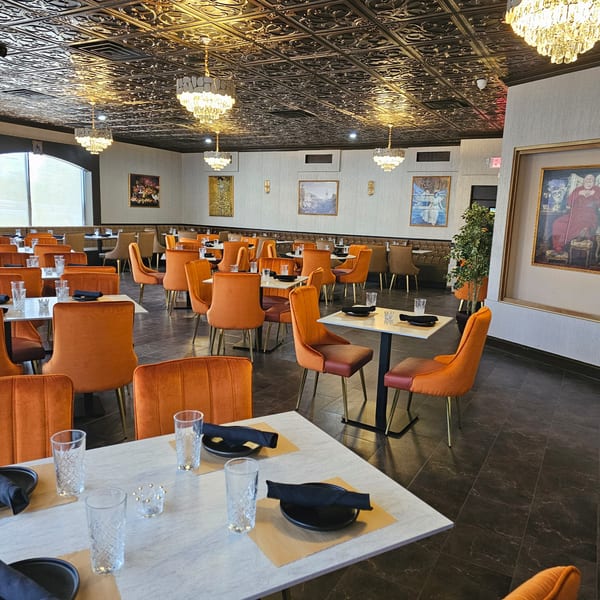 The Opulent Restaurant and Lounge dining room with orange chairs, set tables, and ornate ceiling.