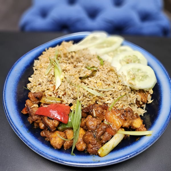 Indian fried rice with chicken, red peppers, and sliced cucumbers on a blue plate.
